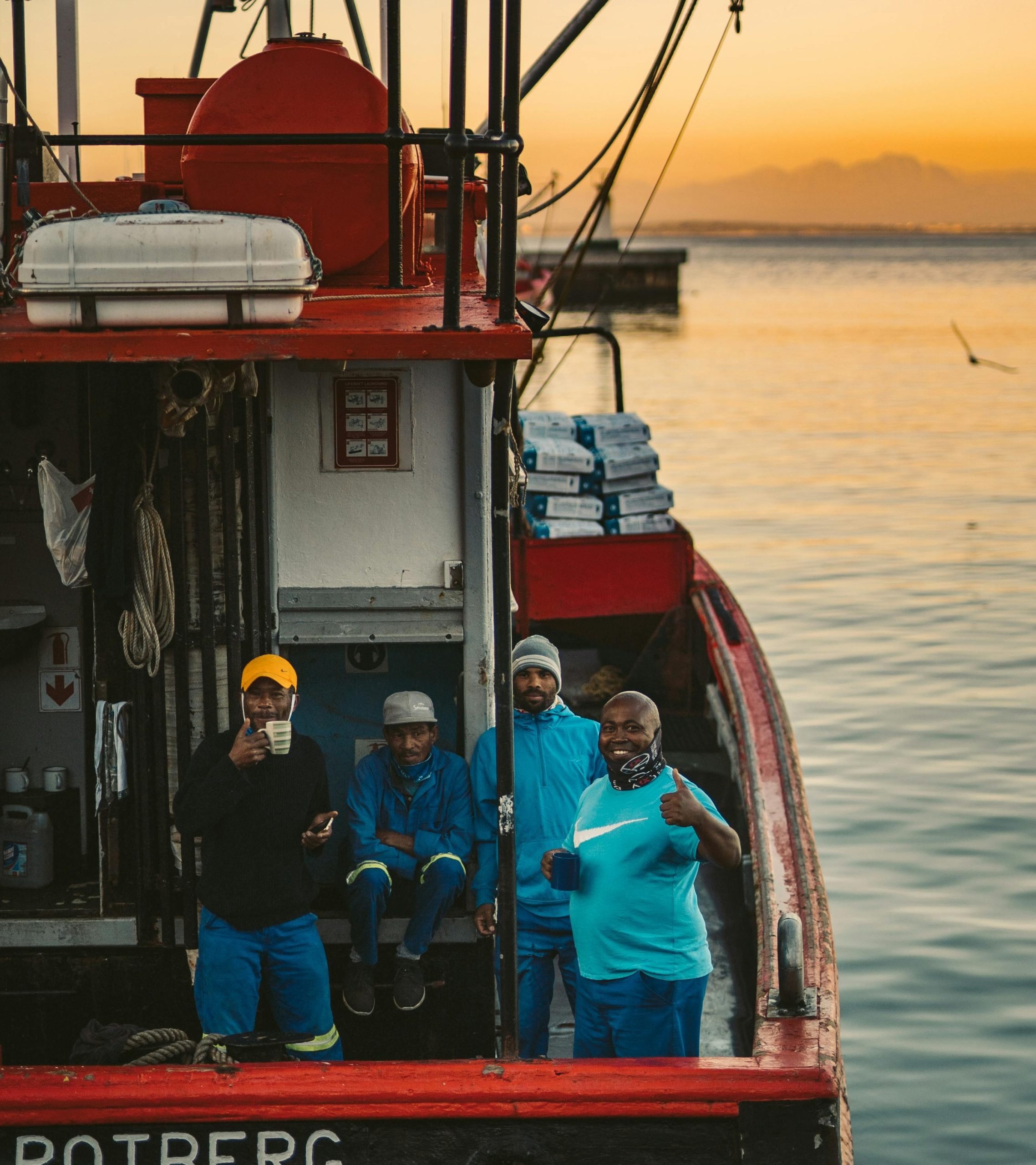 Smiling fishermen on a fishing vessel at sunset, Photo by